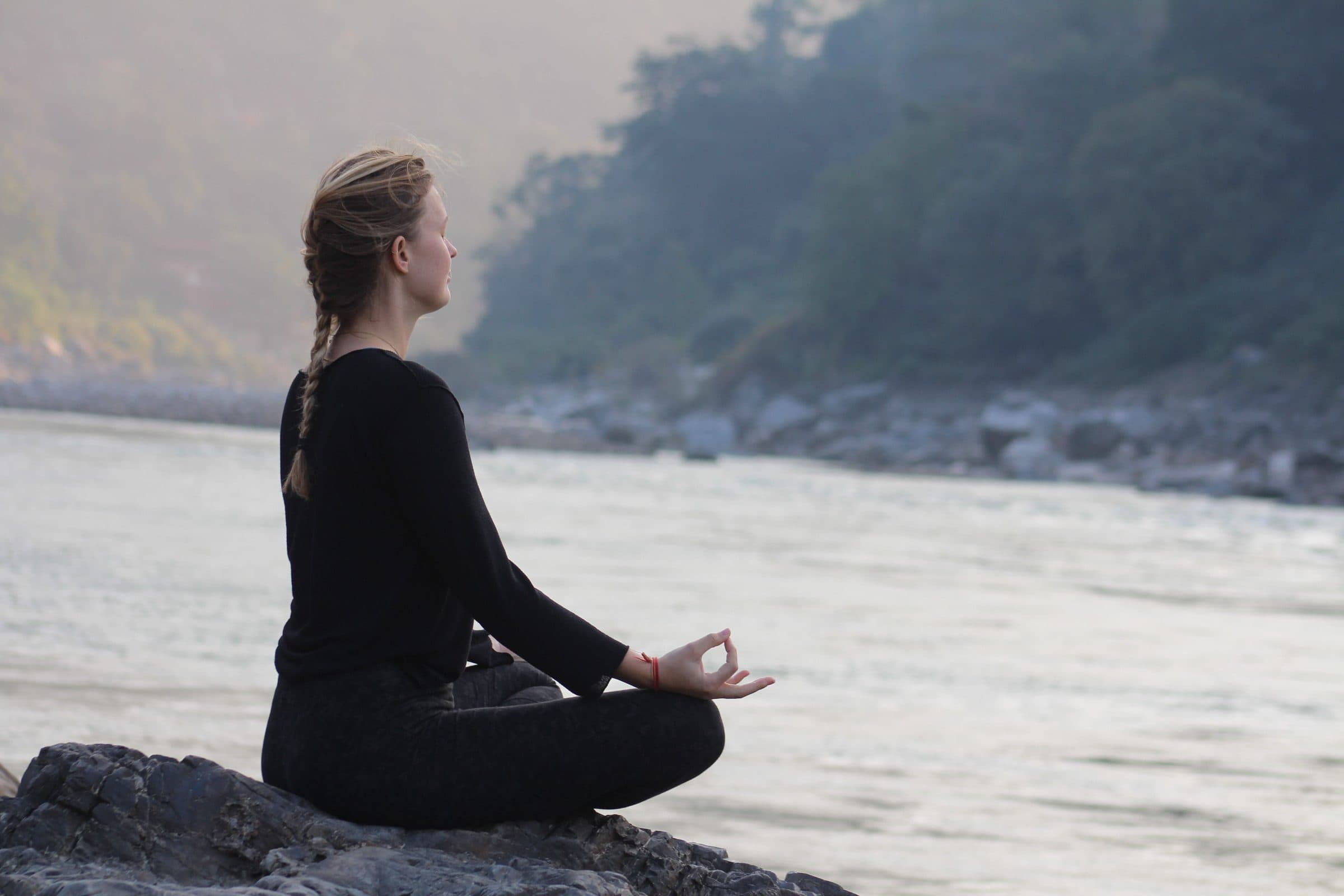 A practitioner meditating by the Ganges at Rishikesh in the soft morning light